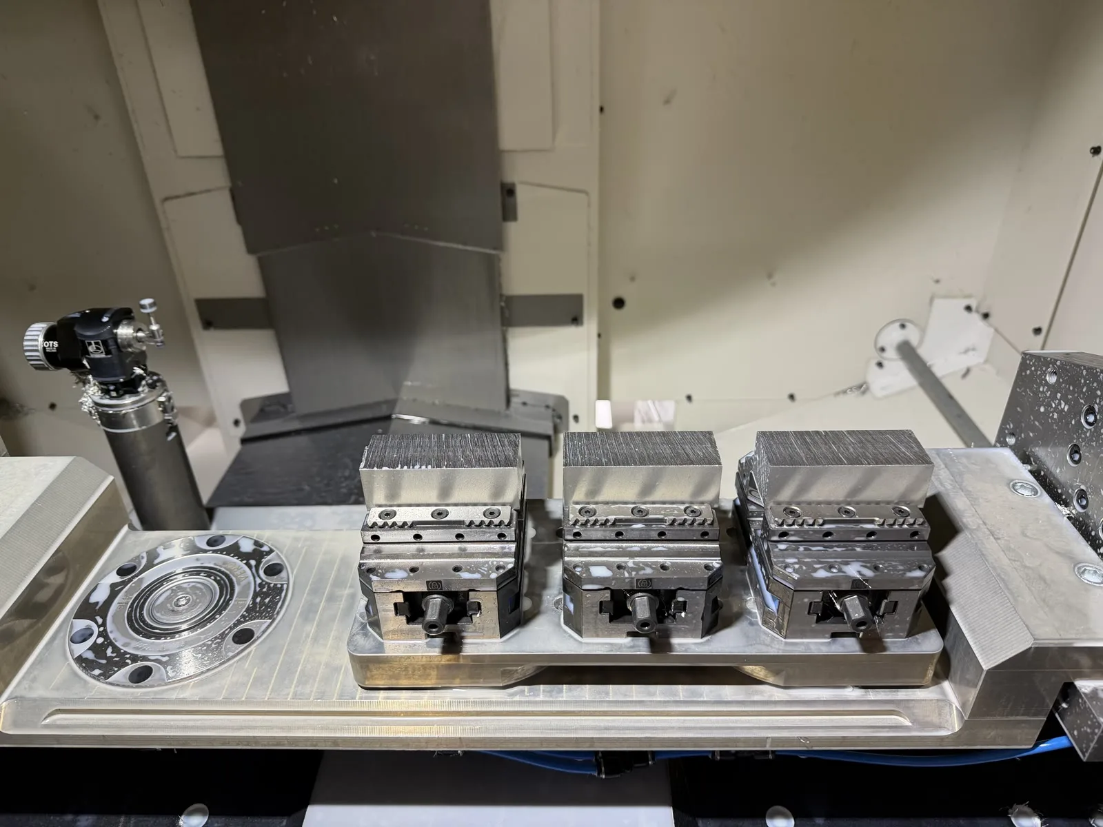 Three aluminium workpieces clamped in separate vises inside a FANUC ROBODRILL