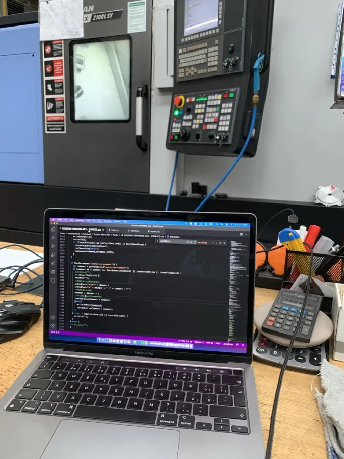 Autodesk Fusion postprocessor code being commissioned beside a FANUC-controlled CNC machine